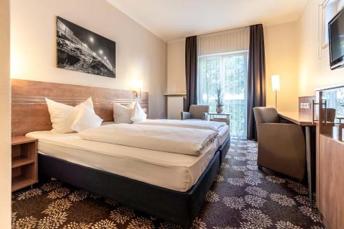 a hotel room with a large bed and a large window at Altstadthotel in Ingolstadt
