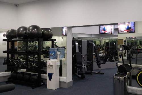 a gym with dumbbells and fitness equipment and televisions at Atrium Hotel Heathrow in Hillingdon
