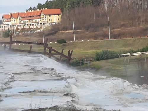 a pond with snow on it with a house in the background at Szalók Spa Apartman Egerszalók in Egerszalók