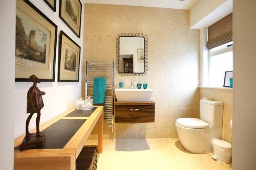 a bathroom with a sink and a toilet and a mirror at Old Croft Stables in Quarndon