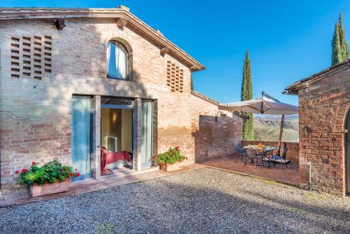 a brick house with a patio and a table at Villa Agriturismo Tenuta la Campana in Asciano