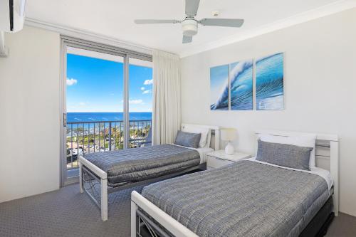 two beds in a room with a view of the ocean at Elouera Tower in Maroochydore