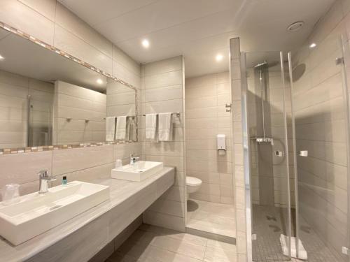 a bathroom with two sinks and a shower at Hôtel Helvétique in Nice