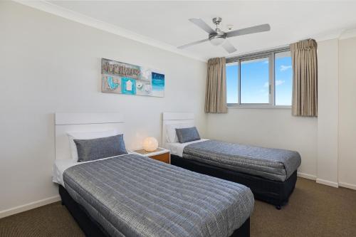a bedroom with two beds and a ceiling fan at Elouera Tower in Maroochydore