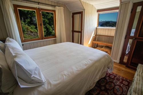 a bedroom with a large white bed and two windows at Casa en Llao Llao con vista al lago y campo de golf in San Carlos de Bariloche