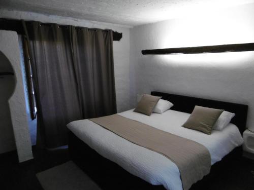 a bedroom with a large bed with white sheets and pillows at Le Relais Des Vieilles Postes in Les Avenières