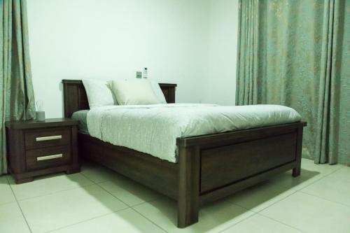 a bedroom with a bed with a wooden frame and a night stand at 90 Independence Avenue in Accra
