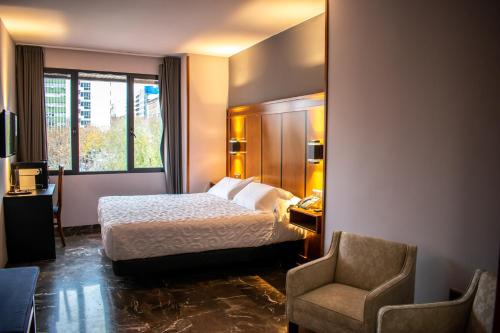 Habitación de hotel con cama y silla en Hotel Condestable Iranzo, en Jaén