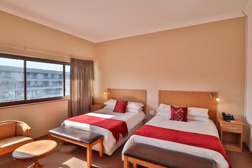 um quarto de hotel com duas camas e uma janela em Gonubie Hotel em Gonubie