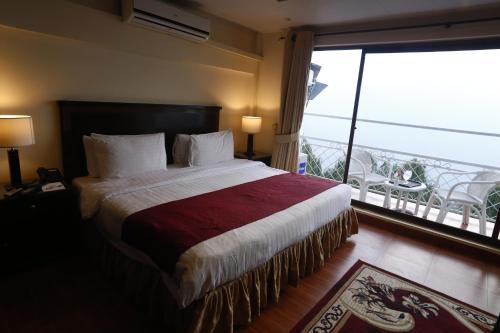 a bedroom with a large bed and a balcony at Hotel One Bhurban in Murree