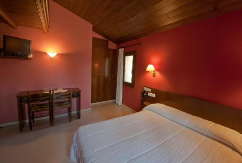 um quarto com uma cama branca e uma parede vermelha em Hotel Can Blanc em Olot