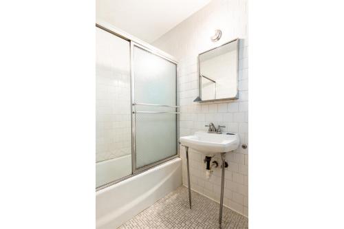 een witte badkamer met een wastafel en een douche bij OYO Hotel Holly Springs MS in Holly Springs