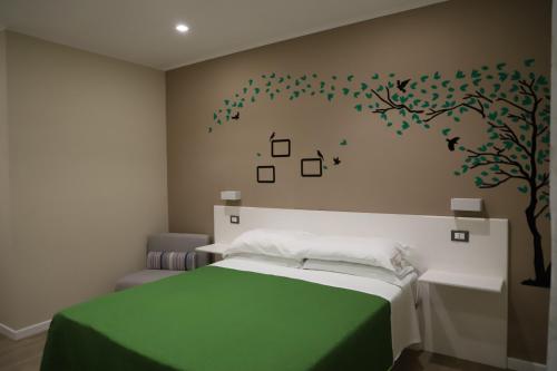 1 dormitorio con 1 cama y un árbol en la pared en Tre Fontane, en Reggio Calabria