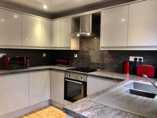 a kitchen with white cabinets and a sink at Rendezvous in Aviemore