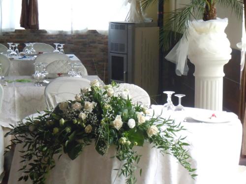 a table with white chairs and flowers on it at Locanda del Lupo in Faenza