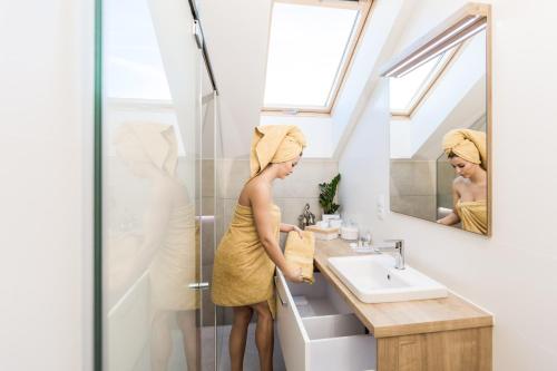 a woman with a towel on her head standing in a bathroom at FLEXIHOME SK - Komenskeho - private parking spot - ultra modern and stylish in Košice