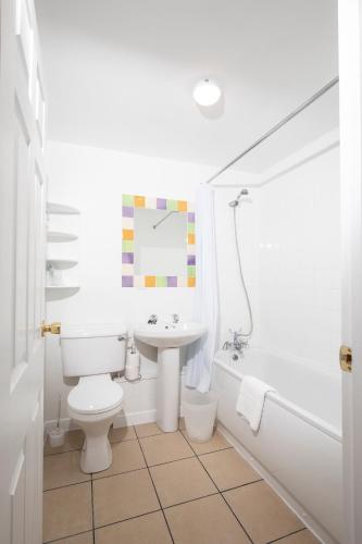 a white bathroom with a toilet and a sink at The Cock Inn Hotel in Sheering