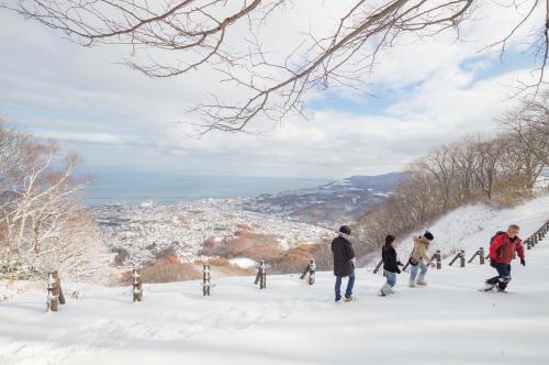 a group of people skiing down a snow covered hill at Otaru Tap Room & Hostel in Otaru