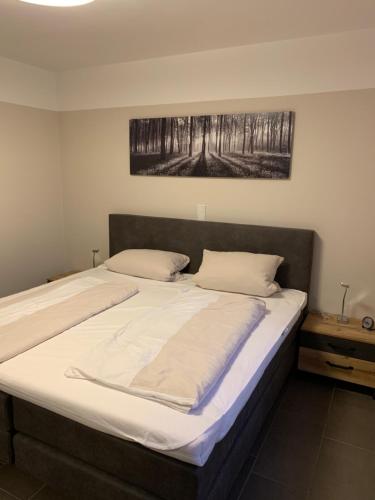 Ferienwohnung Franke في آهاوس: سرير كبير في غرفة نوم مع صورة على الحائط