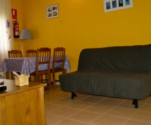 sala de estar con sofá, mesa y sillas en Apartamentos El Castañar, en Hervás