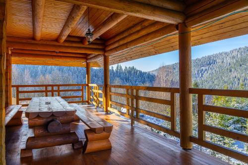 a large wooden porch with a table on a deck at Villa Alpiyka in Slavske