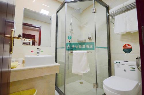 a bathroom with a shower and a toilet and a sink at GreenTree Rizhao Lanshan Coach Station Hotel in Rizhao