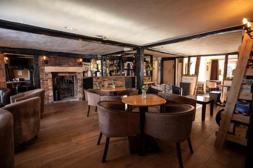 Un restaurante con mesas y sillas y chimenea. en The Cock Inn Hotel, en Sheering