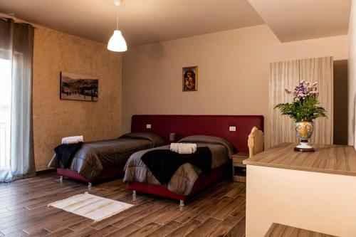a bedroom with two beds and a table in it at Il Carro Comfortable Rooms in San Giovanni Gemini
