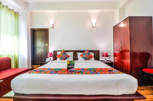 um quarto com uma cama grande e uma cadeira vermelha em FabHotel Greenery View Middle Lingding ICAR Road em Gangtok