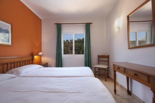 a bedroom with two beds and a desk and a window at PINOS ALTOS 03 in Cala de Sant Vicent