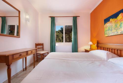 a bedroom with two beds and a desk and a window at PINOS ALTOS 12 in Cala de Sant Vicenc
