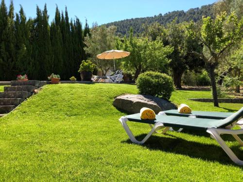 a lawn with a chair and an umbrella at Finca CAN TRUI teresa in Pollença