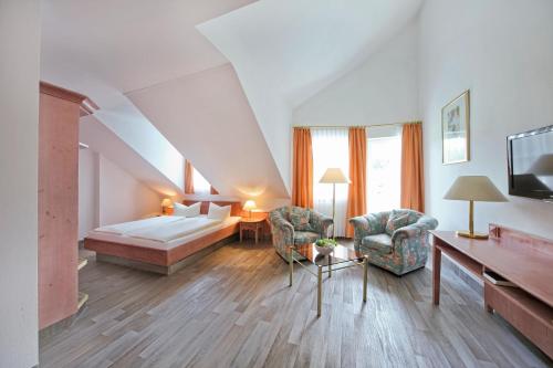 MitwitzにあるWaldhotel Bächleinのベッド、ソファ、椅子が備わるホテルルームです。