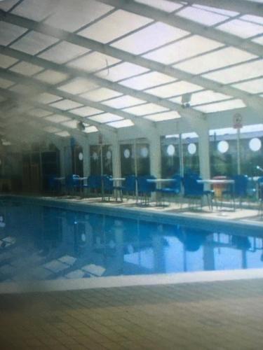 a large swimming pool with blue chairs and tables at The Pet Friendly Pad in Hunstanton