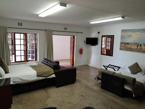 a bedroom with a bed and a couch and a chair at Lifestyle Corner Guesthouse in Musina