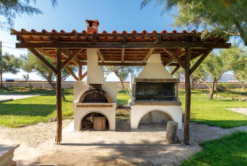 an outdoor pizza oven with a wooden roof at Zefyros Apartments and House in Kissamos