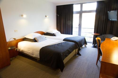 a hotel room with two beds and a window at Best Western Plus Aldhem Hotel in Grobbendonk