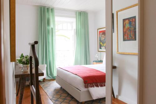 a bedroom with a bed with green curtains and a window at São Paulo Boutique Hotel - SPBH in Tavira