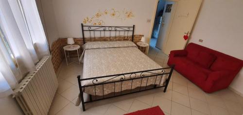 1 dormitorio con 1 cama y 1 sofá rojo en La Casina di Zia Zita en Pieve a Nievole