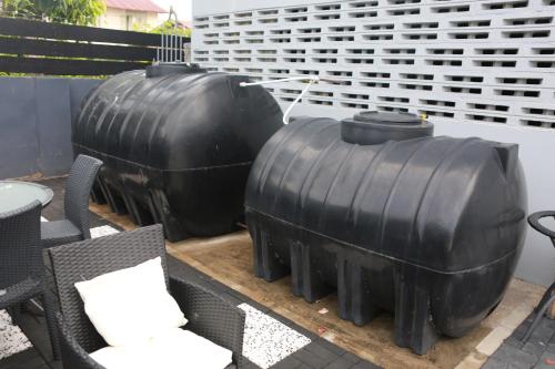 three large black tubes sitting on a table with chairs at Donfarsha Apartments in Paramaribo