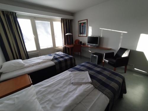 a hotel room with two beds and a chair at West Side Hotel in Turku