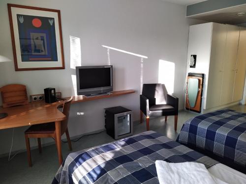 a room with a bed and a desk with a television at West Side Hotel in Turku