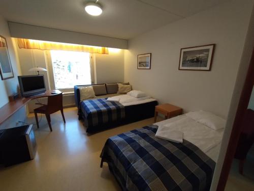 a hotel room with two beds and a desk and a television at West Side Hotel in Turku