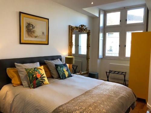 - une chambre avec un lit doté d'oreillers et d'un miroir dans l'établissement La Renaissance au coeur du centre historique, à Beaune