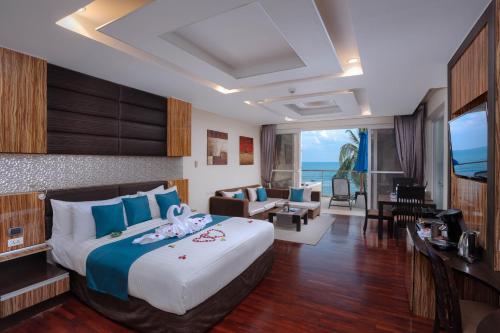 Royal Beach Boutique Resort & Spa Koh Samui - SHA Extra Plus في شاطئ لاماي: غرفة نوم بسرير كبير وغرفة معيشة