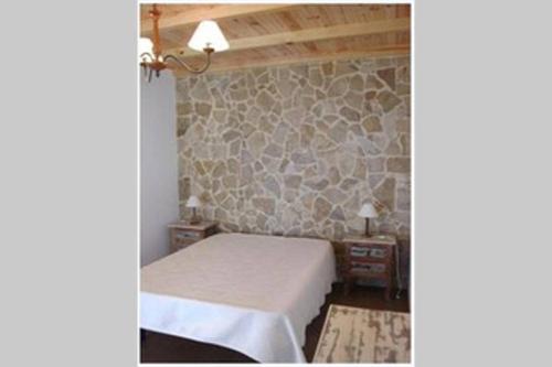 a bedroom with a bed and a stone wall at Casa das conchas 2 in Buarcos