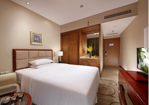 a bedroom with a large white bed and a television at City Hotel Xiamen-Free Welcome Fruits in Xiamen