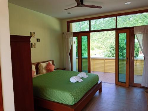 a bedroom with a green bed and a large window at Yen~Yen B&B in Prachuap Khiri Khan