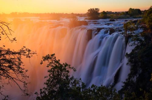 a picture of a waterfall at sunset at Mbano Manor Hotel Victoria Falls in Victoria Falls