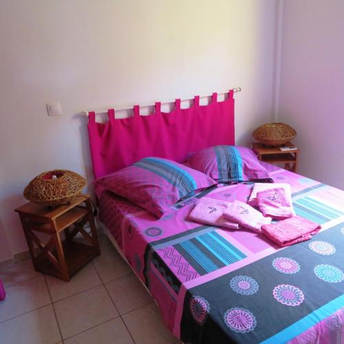 a bedroom with a bed with pink sheets and pillows at Gite KAZ A LILINE in Le Moule
